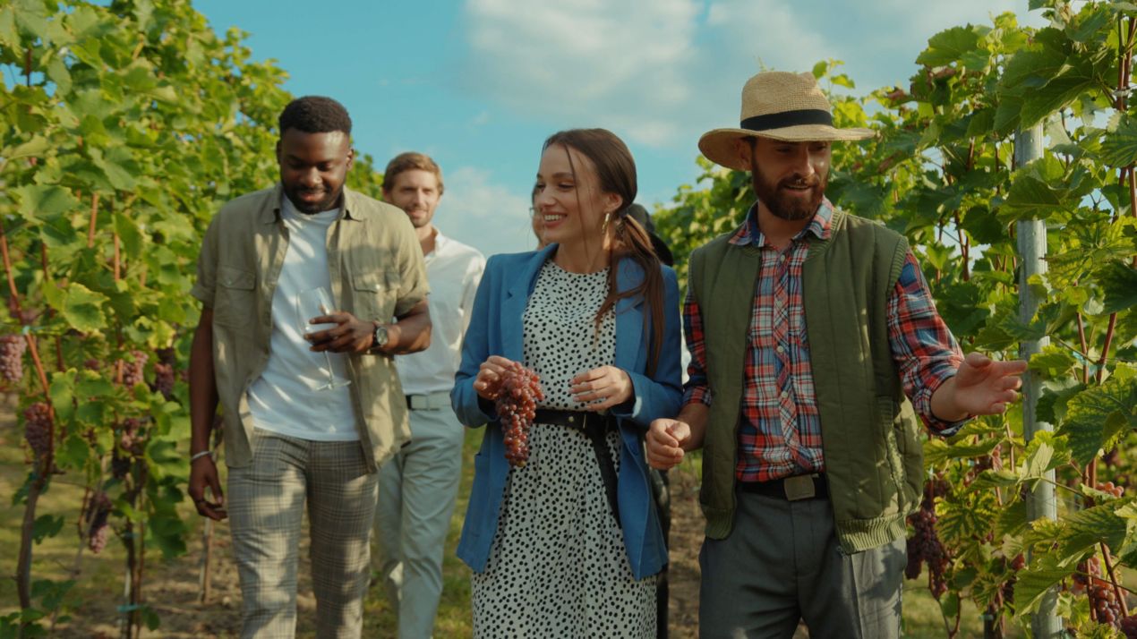 Gruppe junger Erwachsener bei einer Fuehrung durch die Weinberge des Weingut Ziereisen, mit Trauben und Weinglaesern in der Hand