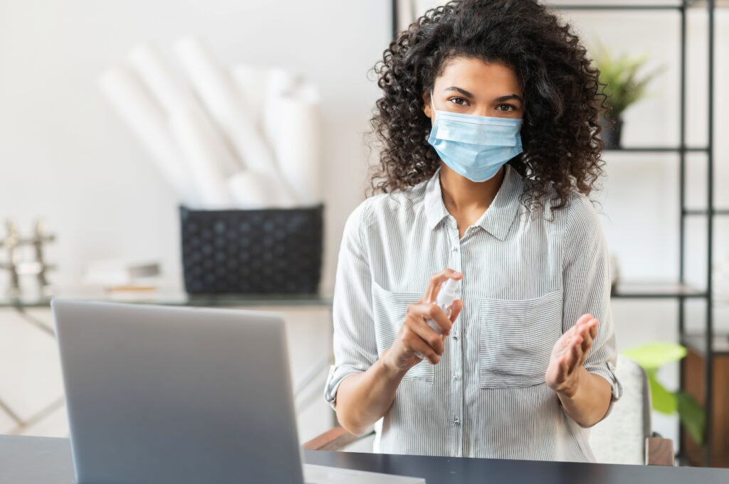 Frau am Laptop während einer E-Learning Hygiene-Schulung, desinfiziert sich die Hände