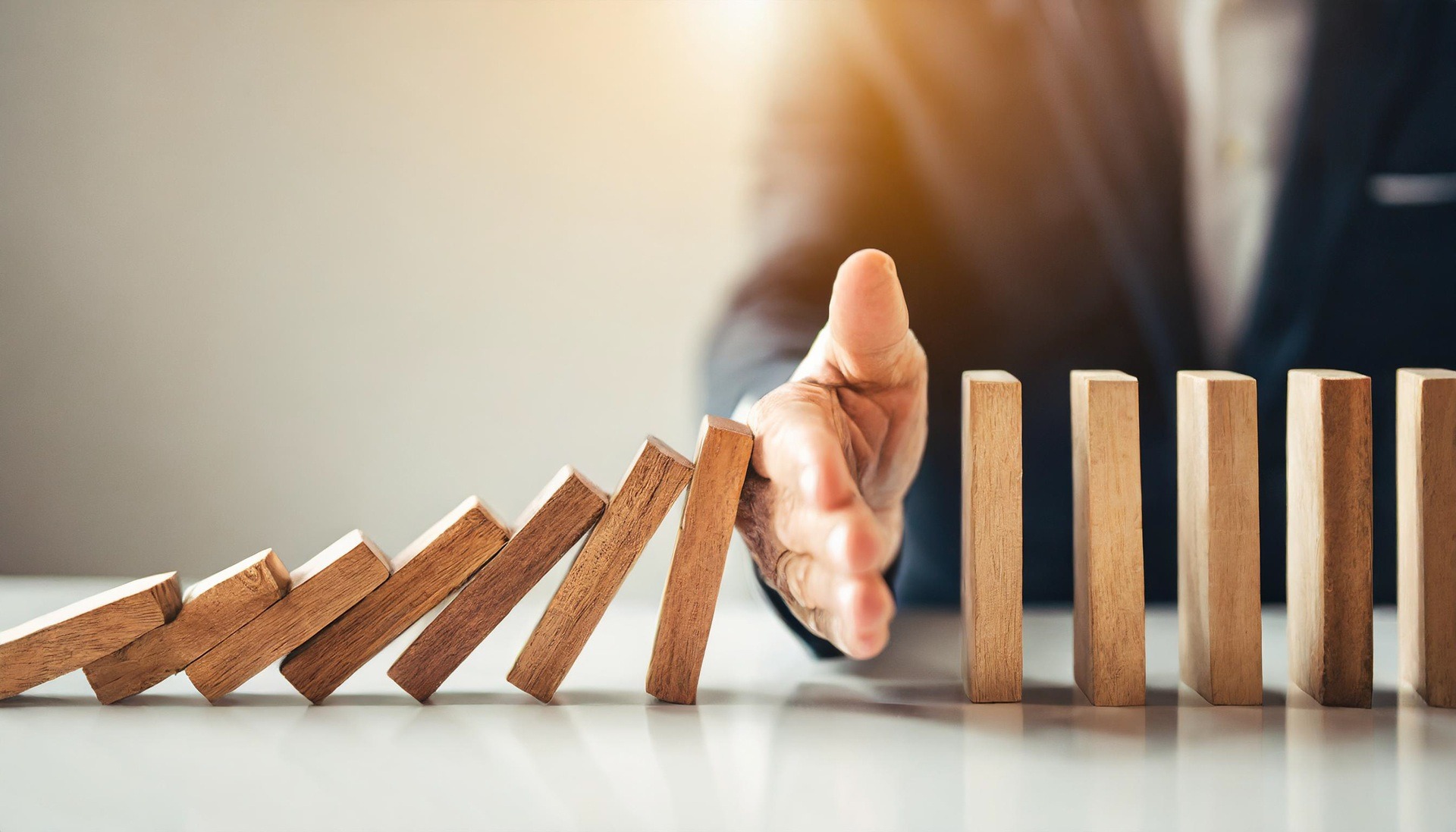 Hand stoppt fallende Dominosteine | Pflegehilfskraft Ausbildung